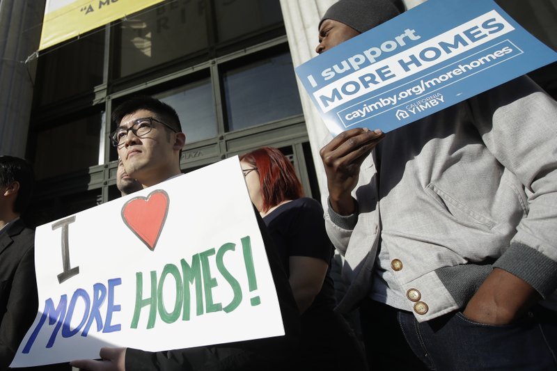 Protestors hold signs demanding housing solutions